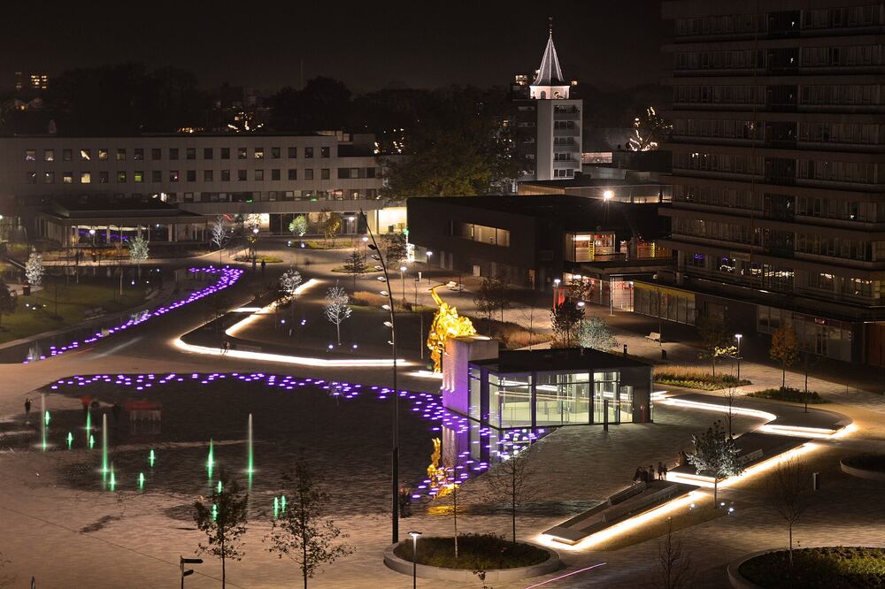 Het Raadhuisplein in Emmen bij avond, met verlichte lichtkunst langs het water