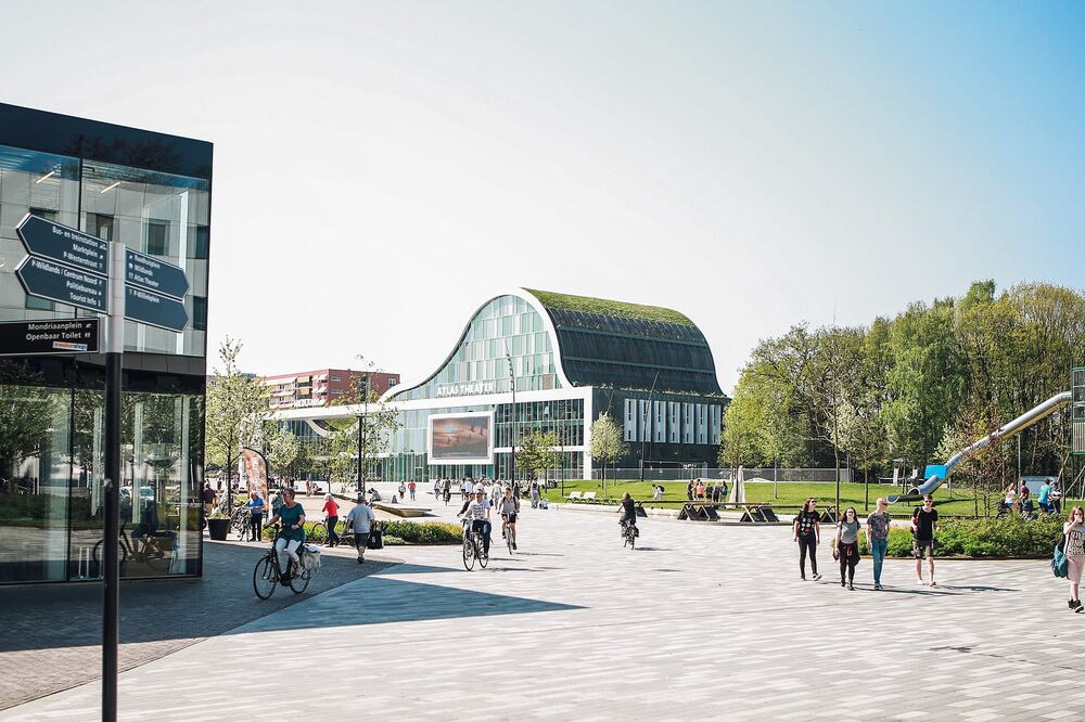 Het Raadhuisplein in Emmen met wandelaars en de groene entree van Wildlands